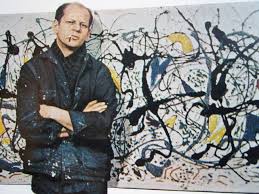 A photo of Jackson Pollock in front of a painting.